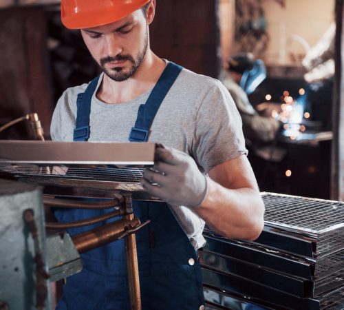 Portrait of a young worker in a hard hat at a large waste recycling factory. The engineer monitors the work of machines and other equipment.